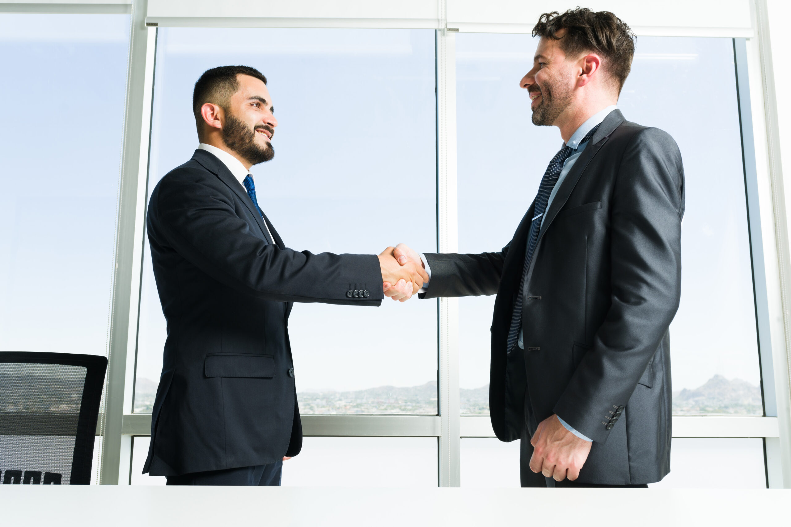 Professional business executives shaking hands during collaborative meeting